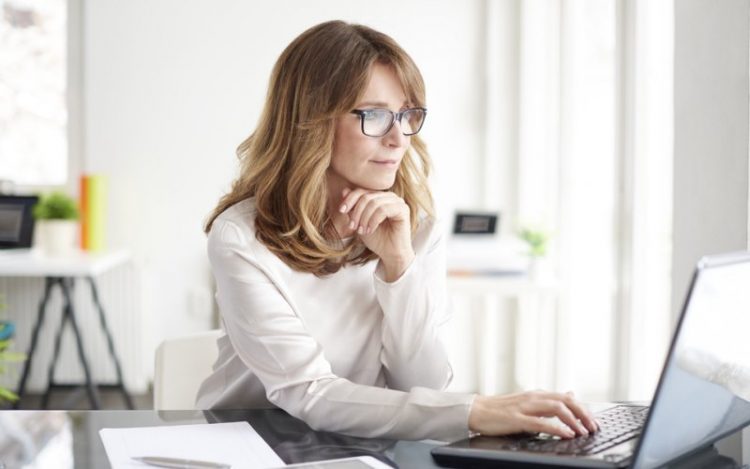 A lady sitting at a desk using a computer to look at trademarks